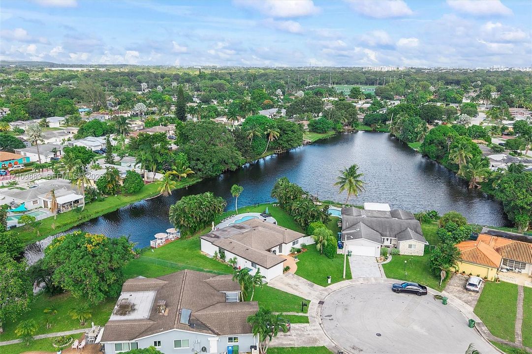 Aerial perspective featuring expansive waterfront positioning, cul-de-sac placement, mature landscaping, and private in-ground pools