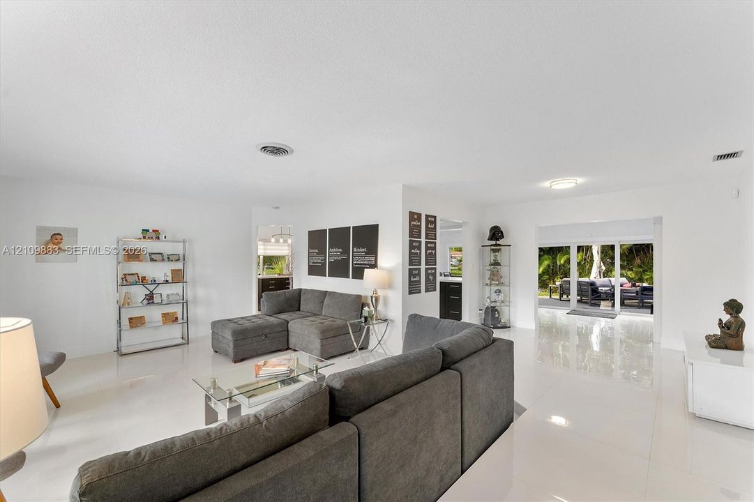 Open-concept interior featuring polished tile flooring, recessed ceiling lighting, and large sliding glass doors providing outdoor access