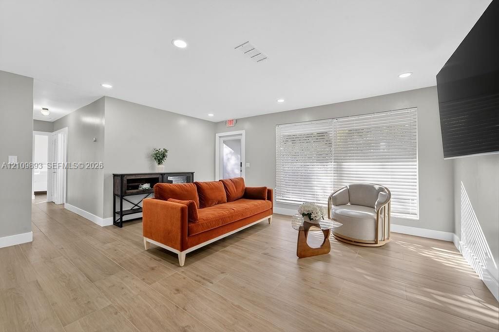 Interior living space featuring wood-finish flooring, recessed lighting, and large windows with horizontal blinds