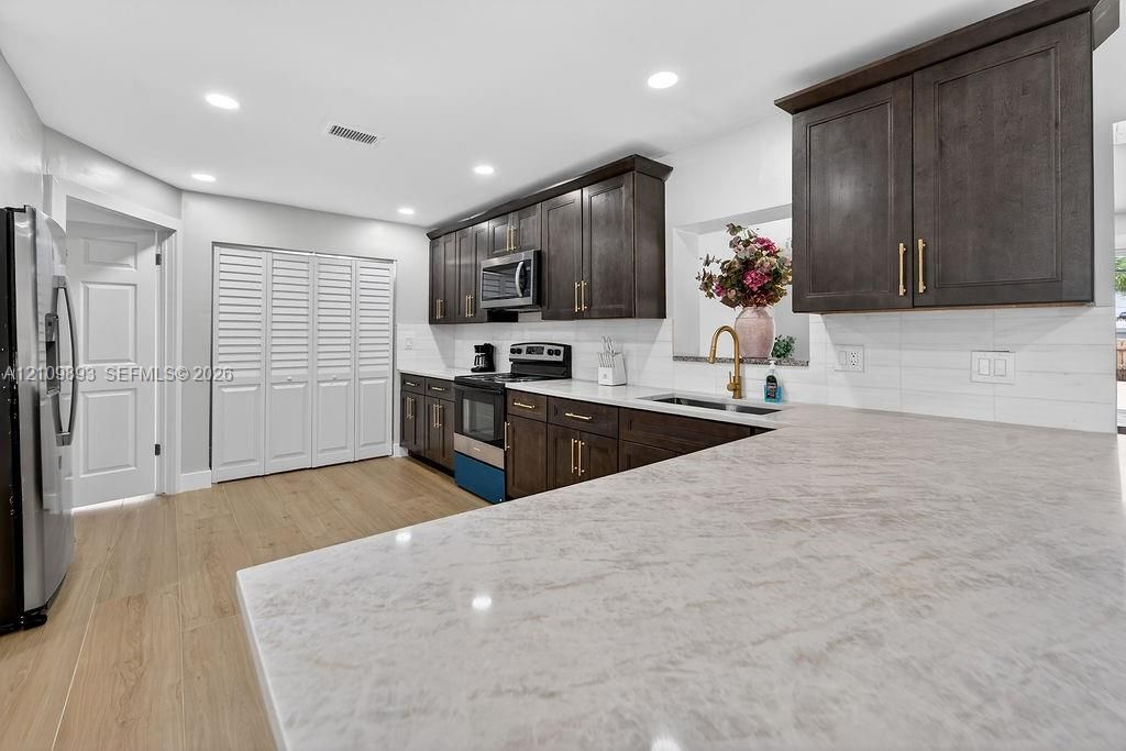 Kitchen featuring dark wood-finish cabinetry, solid-surface countertops, recessed lighting, and wood-finish flooring