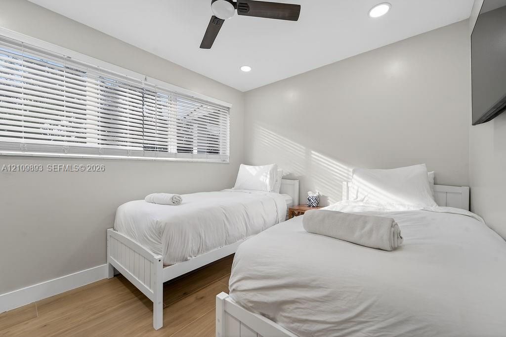 Neutral-toned interior featuring wood-finish flooring, a ceiling fan with integrated lighting, recessed lighting, and horizontal window blinds