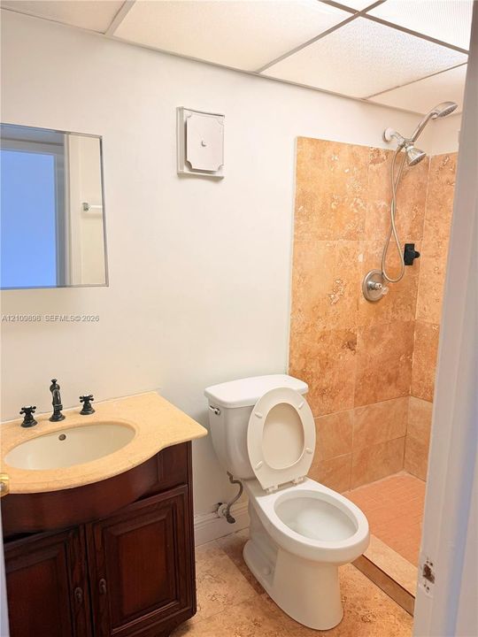Vanity with a solid surface countertop, drop-in sink, and dark wood-finish cabinetry featuring a wall-mounted mirror