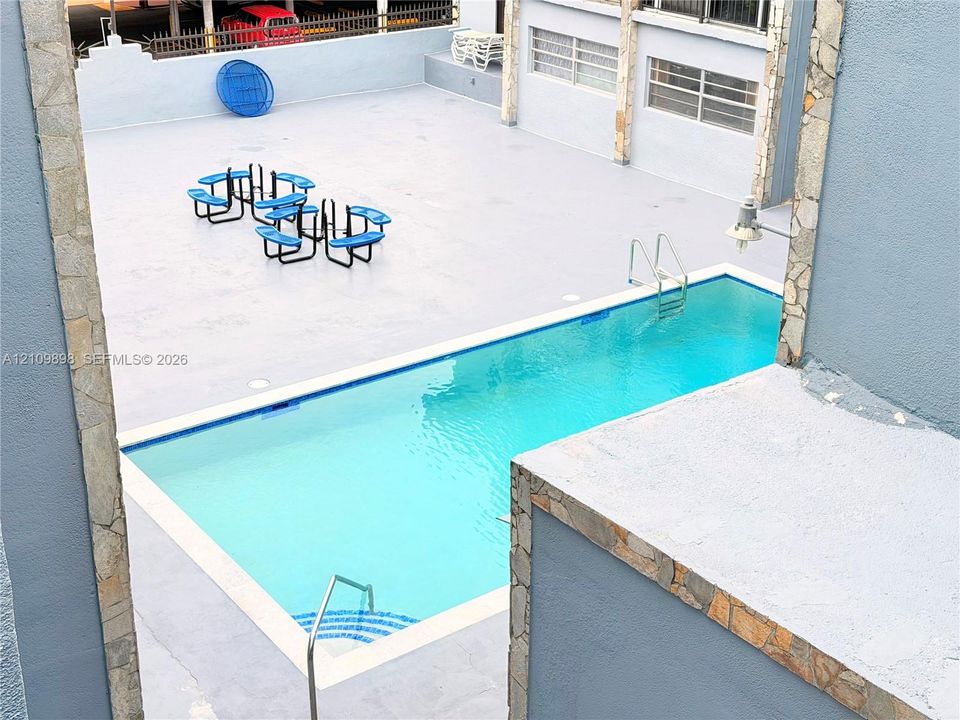 Rectangular swimming pool featuring metal ladders and masonry accents on the surrounding exterior wall