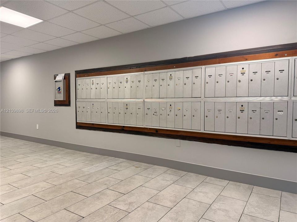 Integrated metal mail center featuring a wood-trim mounting and neutral tile flooring