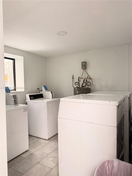 Dedicated laundry area featuring tile flooring, recessed lighting, and a window for natural light