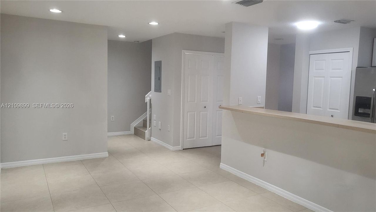 Neutral tile flooring, recessed lighting, and a breakfast bar counter featuring a pass-through opening