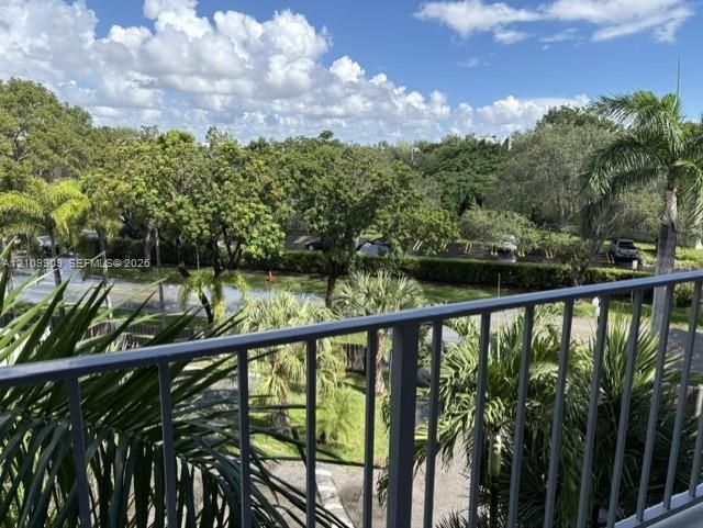 Elevated balcony featuring a metal railing, mature palm trees, and native vegetation