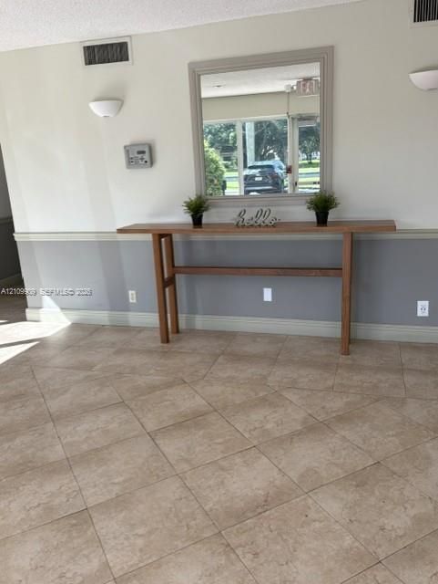 Neutral-toned tile flooring, two-tone wall paint, built-in wooden console, wall-mounted half-moon lighting fixtures, and a large framed mirror