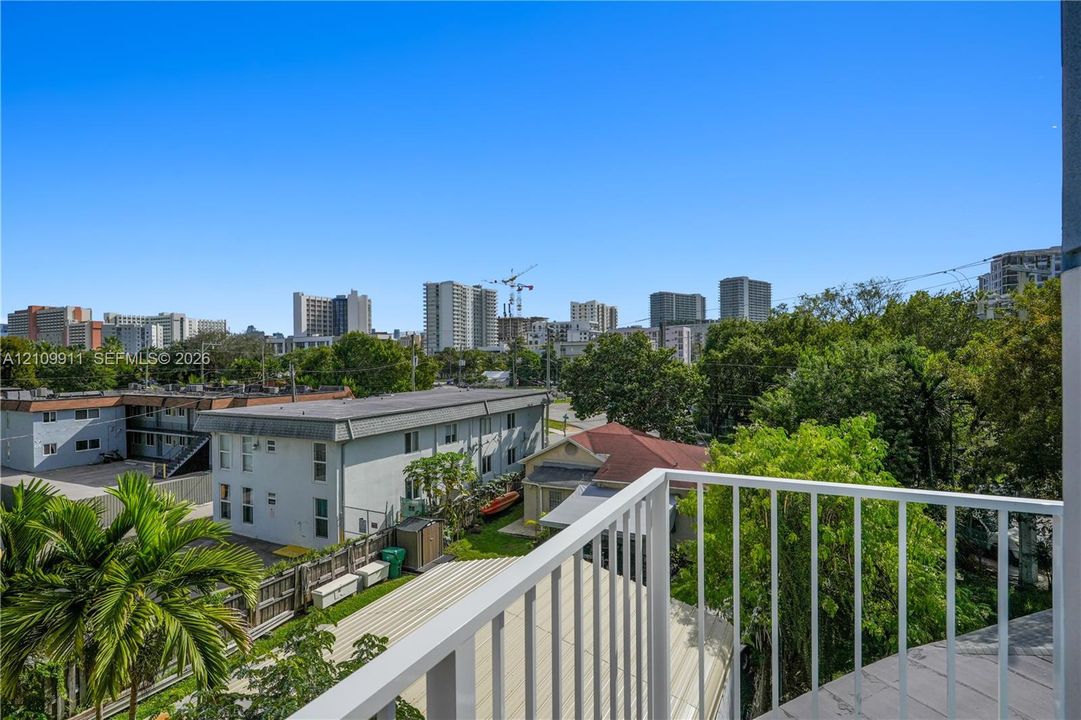 Elevated balcony featuring a white metal railing, tile flooring, and urban scenery