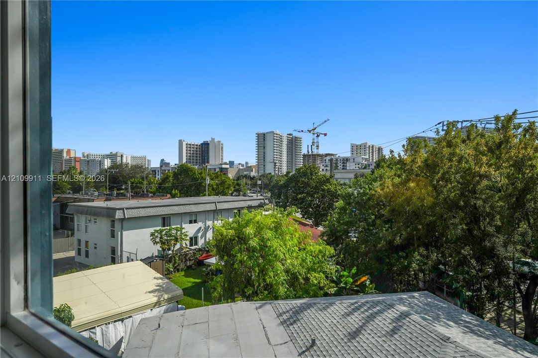 Exterior perspective featuring an urban skyline, mature trees, and shingle roofing