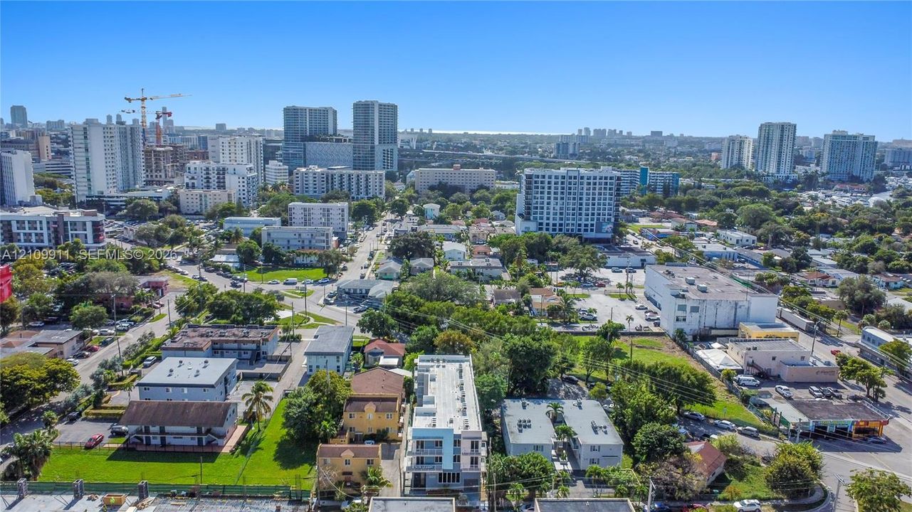 Aerial perspective featuring an urban landscape with multi-story buildings, dense mature tree canopy, and established infrastructure