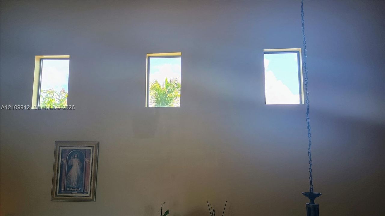 High-reaching walls featuring three clerestory windows and a decorative hanging light fixture