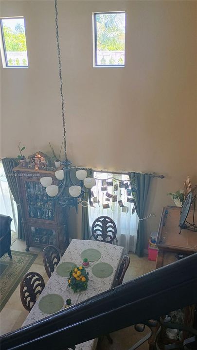 Double-height ceiling featuring high-reaching windows and a multi-arm chandelier