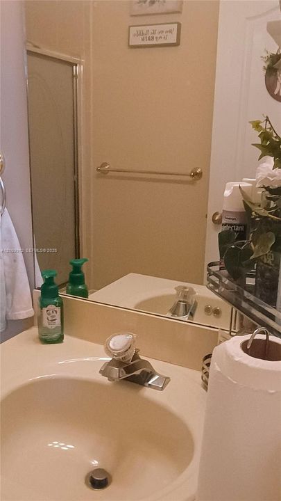 Bathroom vanity featuring an integrated countertop and basin, single-handle faucet with a clear knob, wall-mounted mirror, and metal towel bar