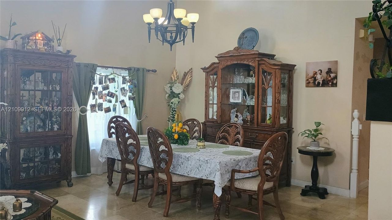 High-ceilinged room featuring natural stone flooring, an intricate metal chandelier, and white-painted interior architectural trim