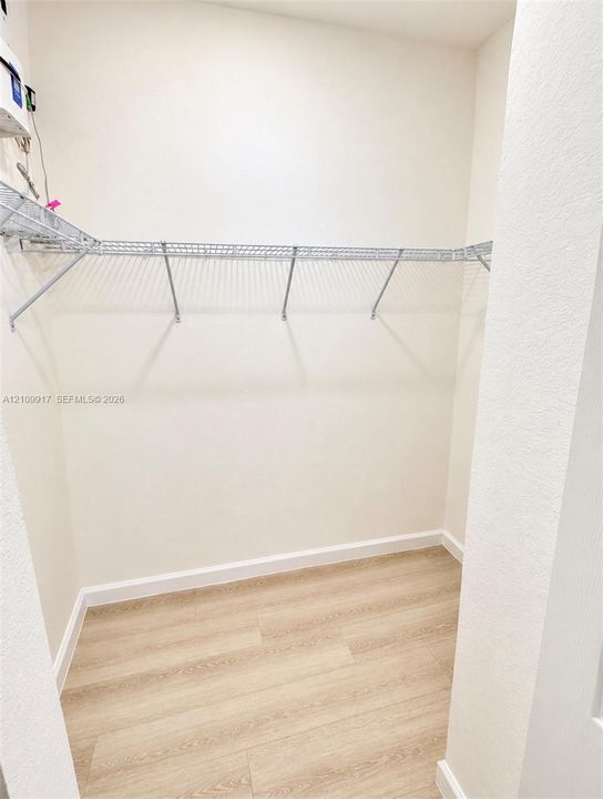 Storage space featuring wood-finish flooring and wall-mounted wire shelving
