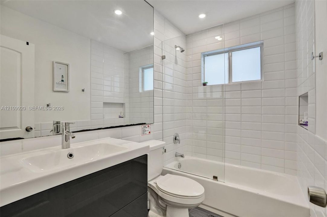 Residence 1753 (Right Side) – Bathroom 2 featuring sleek subway tile, a frameless glass shower enclosure, and a low-profile bathtub.