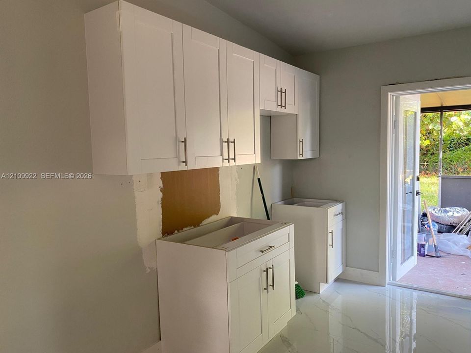 White shaker-style cabinetry with satin nickel hardware and large-format polished tile flooring