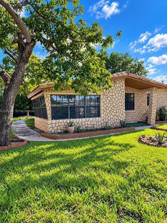 Exterior featuring stone veneer siding, concrete walkway, multi-pane windows, and tile roofing