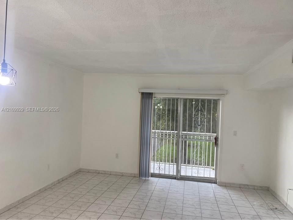 Neutral tile flooring, sliding glass door, decorative metal security gate, and pendant lighting fixture
