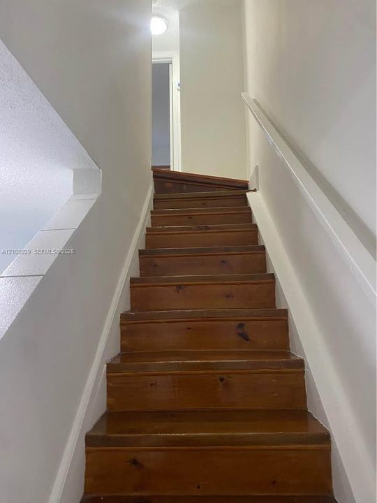 Staircase featuring natural wood treads and white-painted handrails
