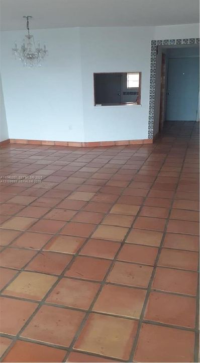 Terracotta tile flooring, decorative tile door surround, pass-through window, and crystal-style chandelier