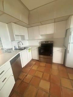 Kitchen featuring white cabinetry, terracotta tile flooring, stainless steel range and dishwasher, and a dual-basin sink with a gooseneck faucet