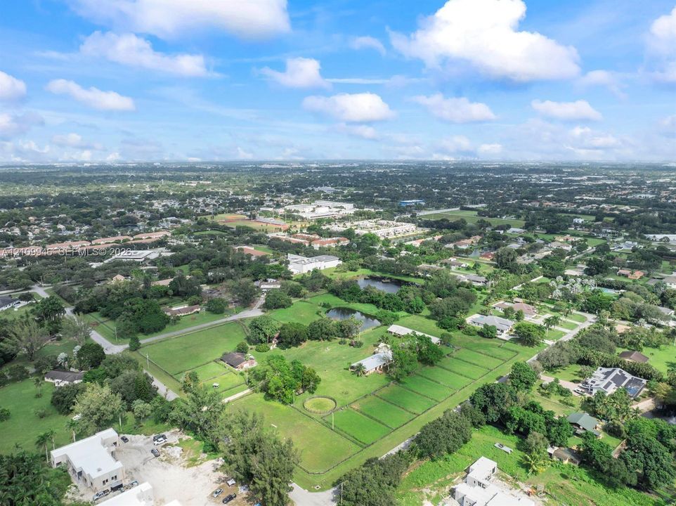 Aerial view of expansive property featuring mature trees, multiple ponds, and fenced perimeter
