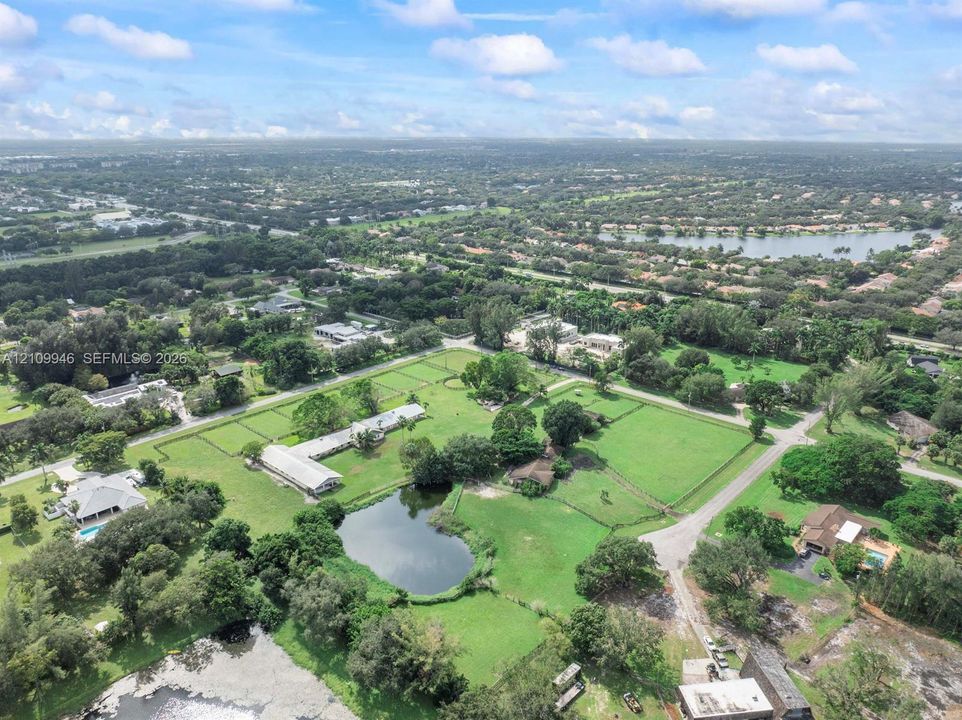 Expansive acreage featuring multiple fenced paddocks, a private pond, and established perimeter landscaping