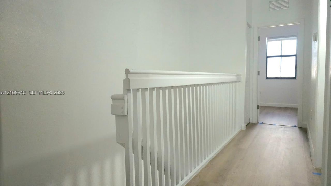 Staircase featuring a white-painted wooden balustrade and handrail, complemented by light-toned wood-finish flooring