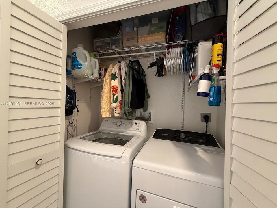 Laundry closet featuring white louvered doors and integrated wire shelving for overhead storage