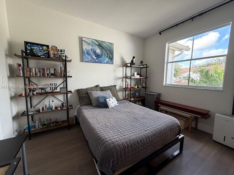Bedroom featuring wood-finish flooring and a large, multi-pane window with natural light