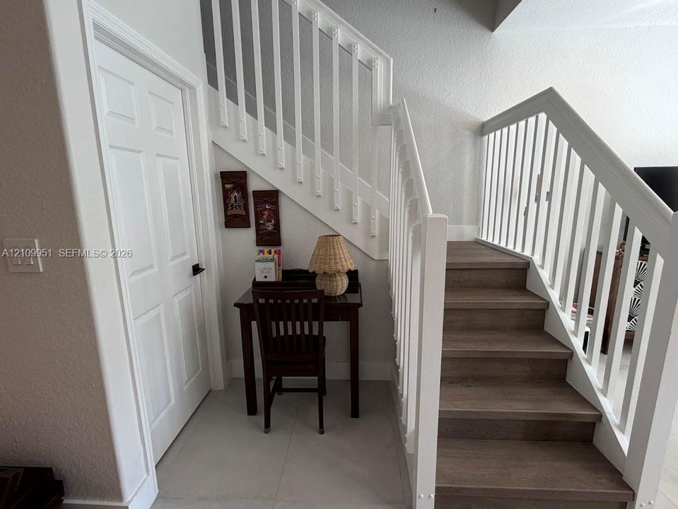 Staircase featuring wood-finish treads, white structural railings, and a solid-core panel door