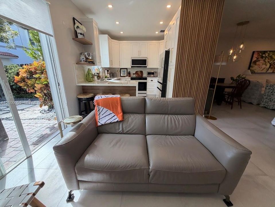 Kitchen featuring white cabinetry, solid-surface countertops, built-in appliances, a breakfast bar, and decorative wood-slat wall paneling