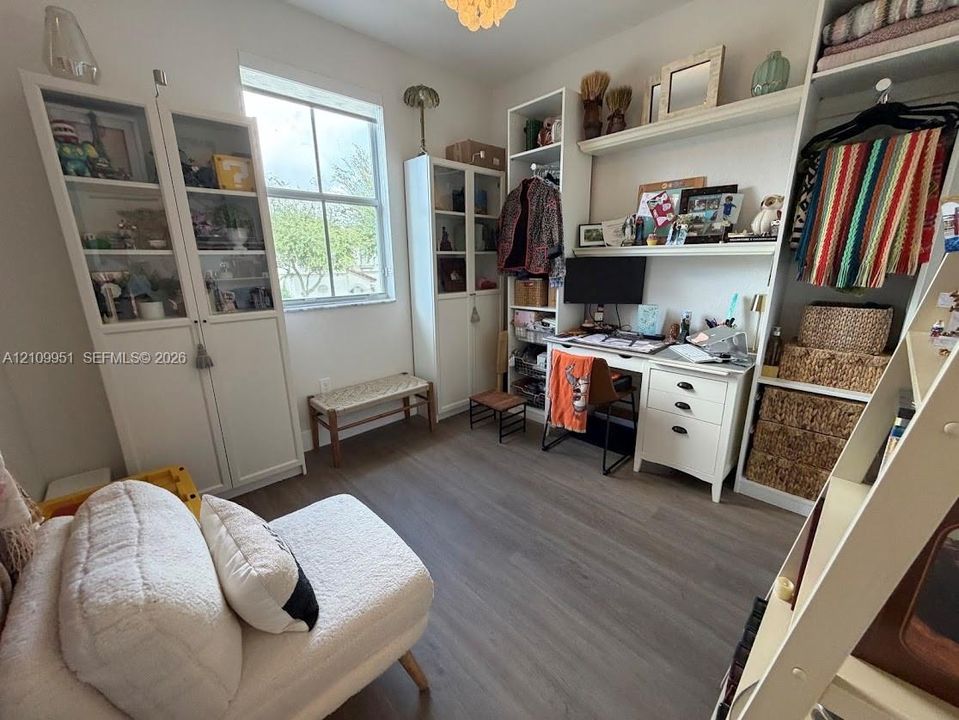Room featuring wood-finish flooring, built-in floor-to-ceiling cabinetry, integrated desk workspace with drawers, and a multi-pane window