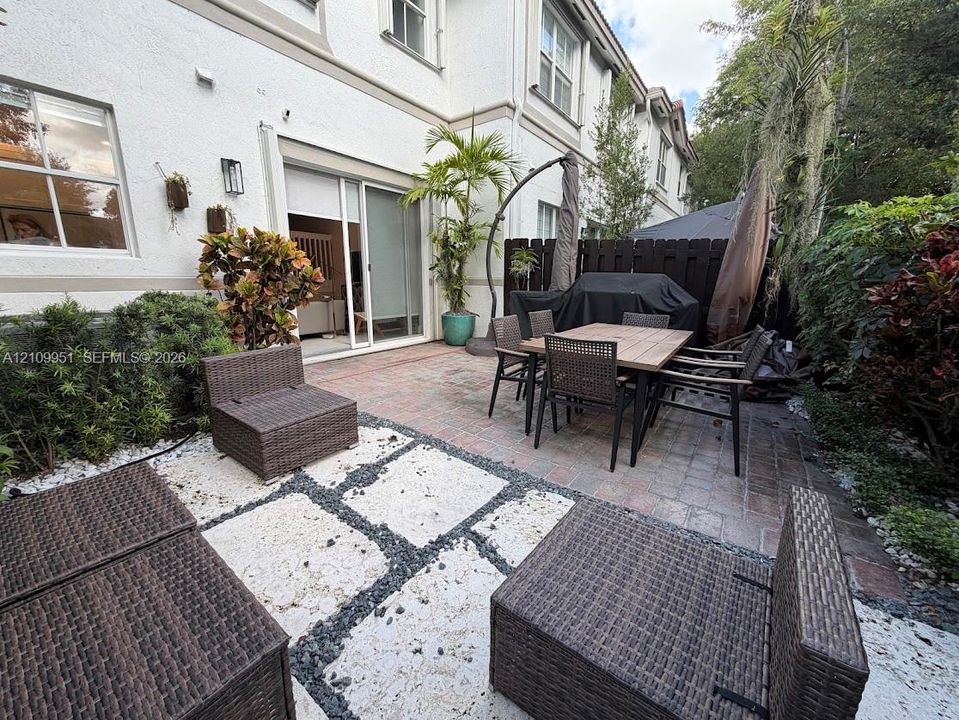 Private courtyard featuring a stone paver patio, decorative gravel inlay, sliding glass door access, and dark wood-tone privacy fencing