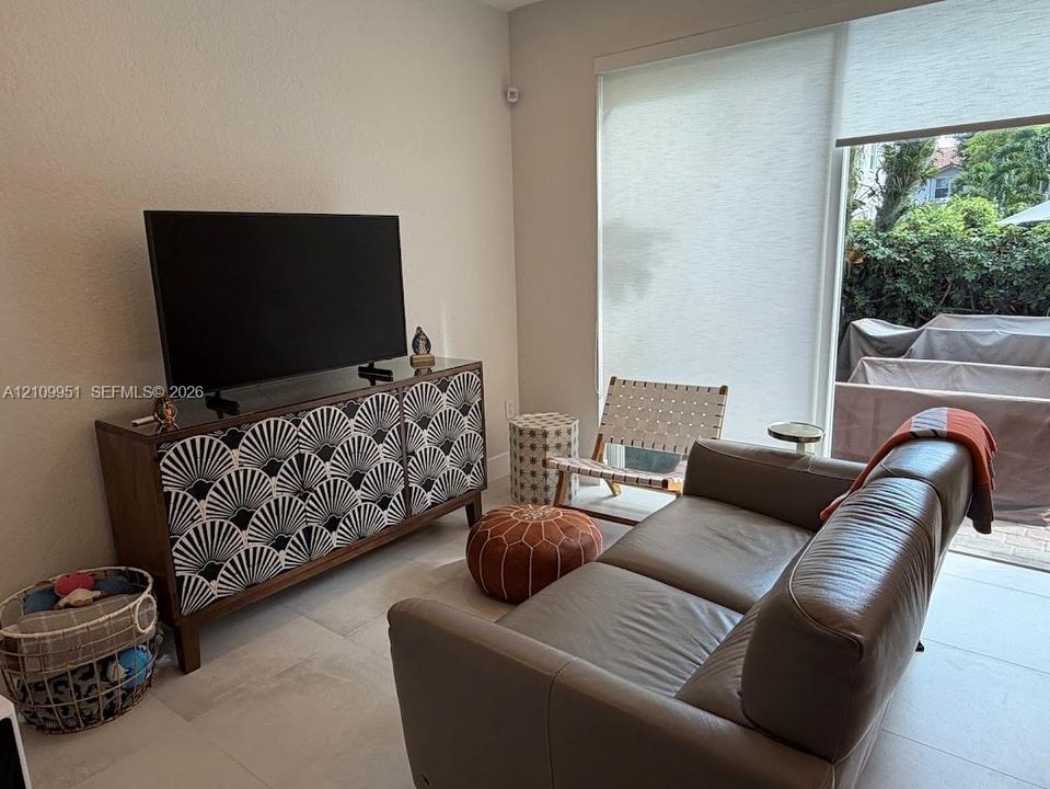 Large-format tile flooring, neutral wall tones, and oversized sliding glass door with integrated roller shades