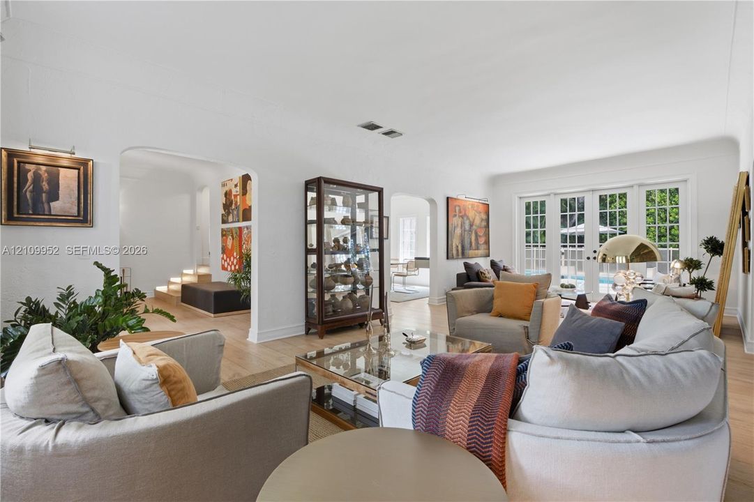 Open floor plan featuring arched doorways, light wood-finish flooring, and multi-pane French doors