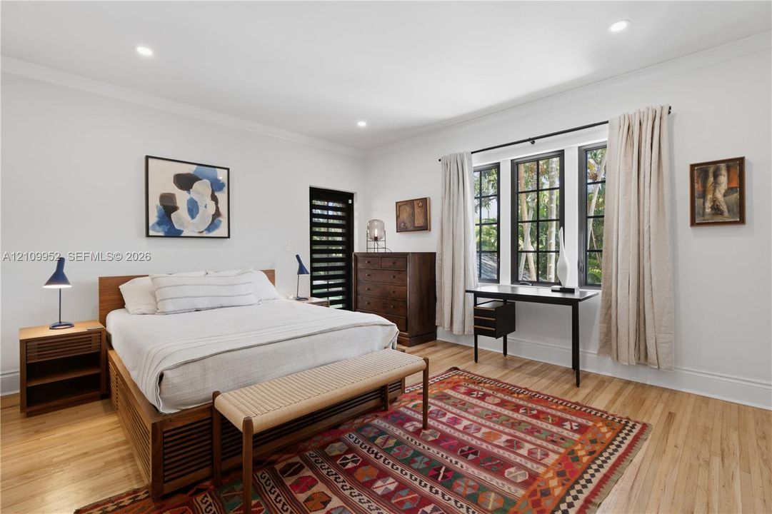 Interior space featuring wood-finish flooring, recessed lighting, multi-pane windows with dark frames, and a dark-toned louvered door