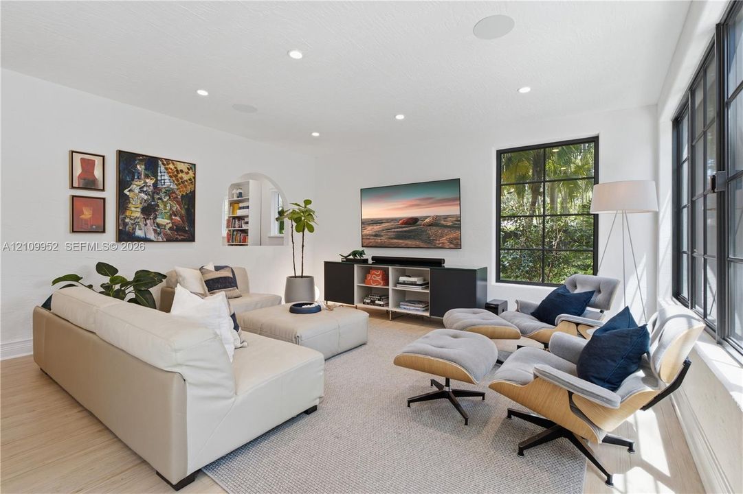 Living area featuring wood-finish flooring, recessed lighting, multi-pane windows with dark frames, and a recessed arched wall niche