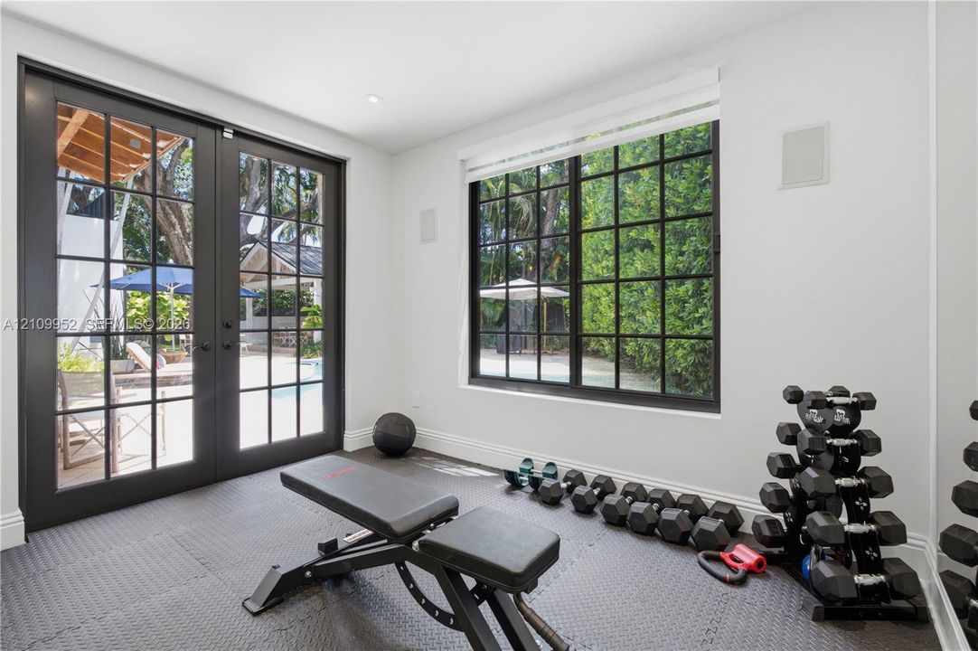 Multi-pane black-framed glass doors, large black-framed picture window, recessed lighting, integrated ceiling speakers, and resilient textured flooring