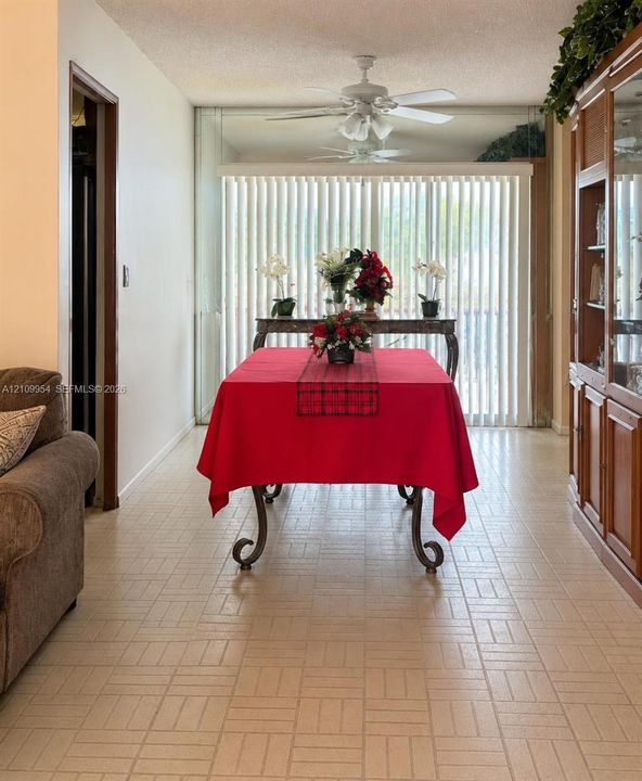 Ceramic tile flooring, built-in wooden cabinetry with glass-front shelving, ceiling-mounted light fixtures with integrated fans, and full-height vertical window blinds