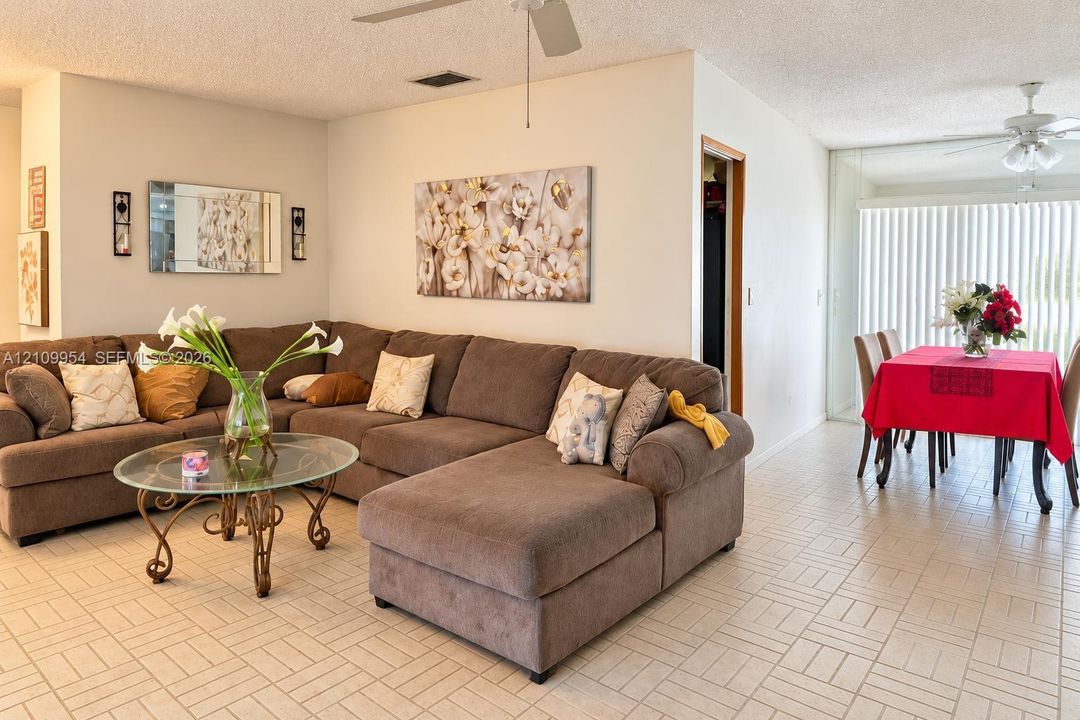 Ceramic tile flooring, dual ceiling fans with light fixtures, and floor-to-ceiling vertical blinds