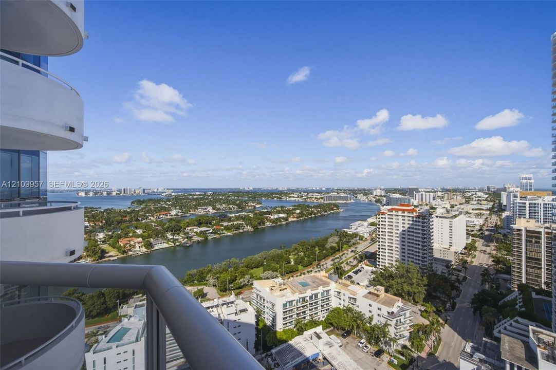 Expansive 29th floor views from covered balcony with metal railing, floor-to-ceiling glass windows, and oceanfront, intracoastal and Biscayne Bay exposures.
