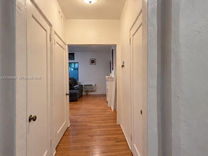 Hallway featuring wood-finish flooring, white paneled doors, and a neutral wall finish