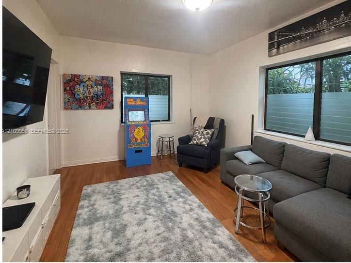 Living area featuring wood-finish flooring, two large windows, and a ceiling-mounted lighting fixture