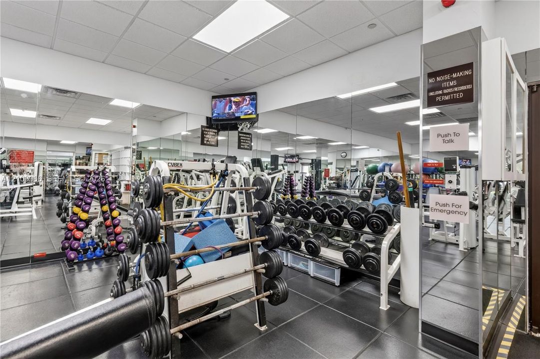 Fitness facility featuring mirrored walls, rubberized flooring, and built-in weight storage racks