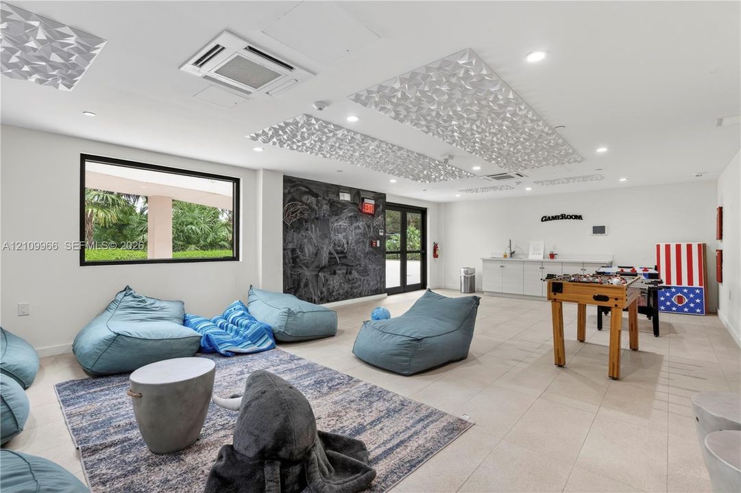 Spacious interior featuring recessed lighting, decorative ceiling acoustic panels, large-format tile flooring, a dark textured accent wall, and built-in cabinetry with a countertop