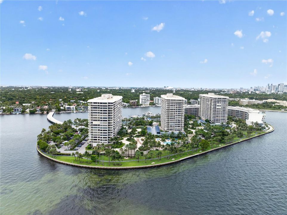Waterfront high-rise community featuring landscaped grounds, palm tree-lined pathways, and expansive shoreline access