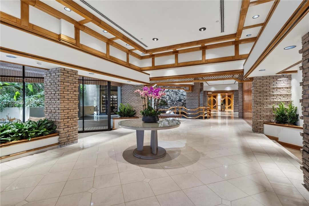 Spacious interior featuring a coffered ceiling with wood trim, decorative brick pillars, tile flooring, and recessed lighting